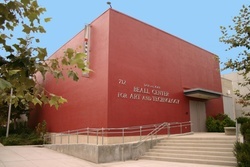 A square, windowless, tomato-red building with concrete steps and ramp leading to its double doors. Lettering on the front wall reads “Don and Joan Beall Center for Art and Technology.”