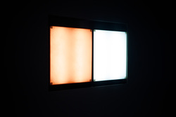 A light box against a dark background. One half is emitting a bright amber glow resembling dawn’s warmer orange light. The other half is a cool white light.